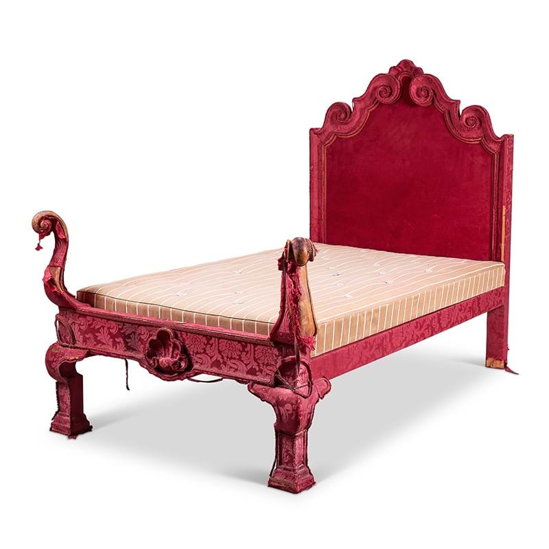 A large red velvet uphostered single bed in the late 17th century style, early 20th century, possibly by Lenygon & Morant