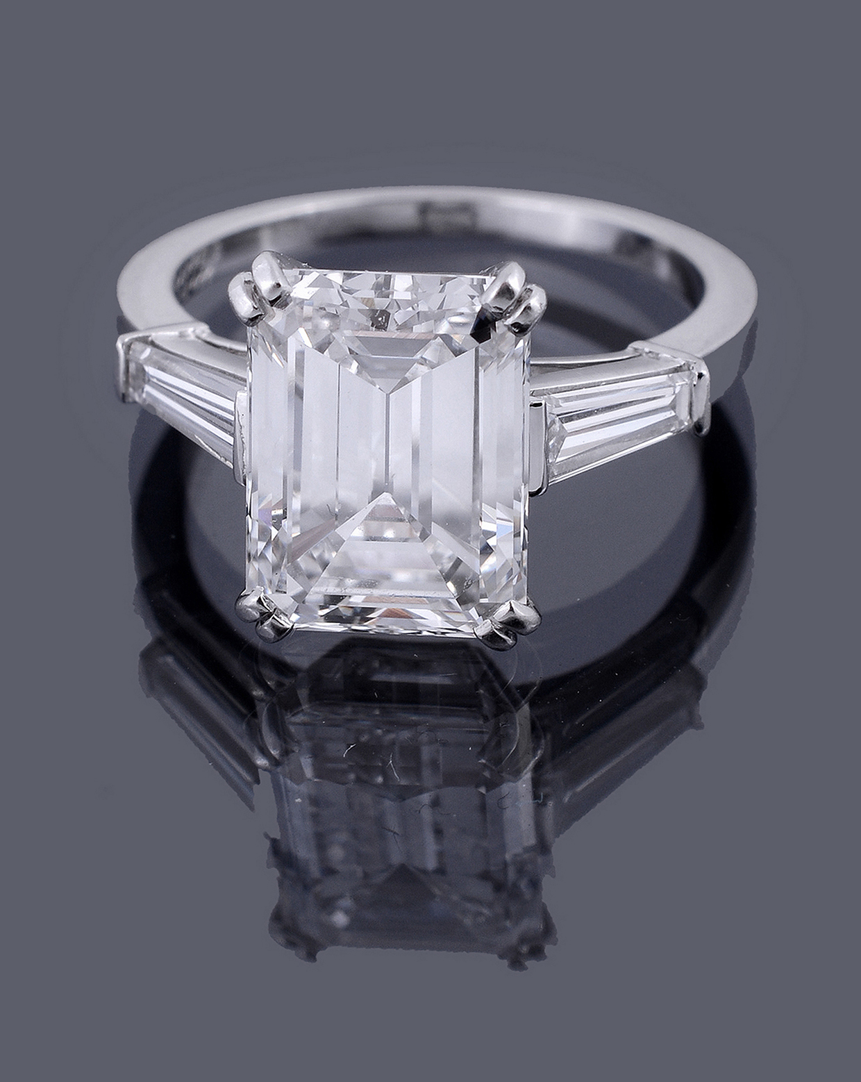 Inline Image - A single stone diamond ring by Van Cleef and Arpels, the step cut diamond with canted corners weighing 4.73 carats, E colour, VS1 clarity, four claw set above tapered baguette cut diamond shoulders, signed Van Cleef & Arpels | Sold at Dreweatts for £130,200