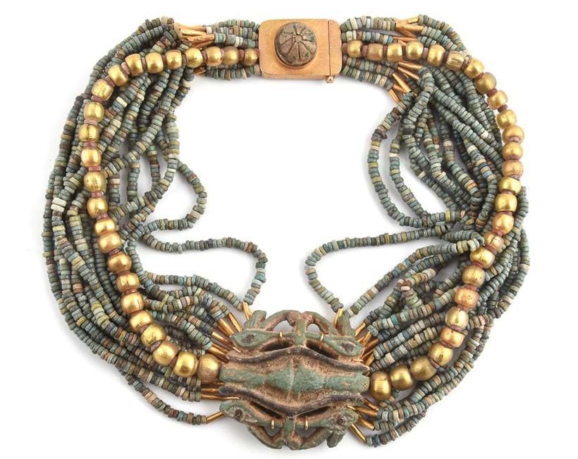 Inline Image - An Egyptian Revival blue faience bead collar necklace, composed of sixteen rows of spacer beads and a gold coloured glass bead row, supporting a blue faience amulent with the Eyes of Horus, on a plaque clasp applied with a carved motif, 40cm long