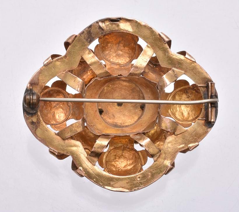 Inline Image - The back of a poorly repaired Victorian brooch, showing the catch has been replaced with an oval base metal patch. The dirty grey areas beneath the catch and pin are soft lead solder, which is always a sign of poor repair. There are also very visible dents and holes in the gold work.